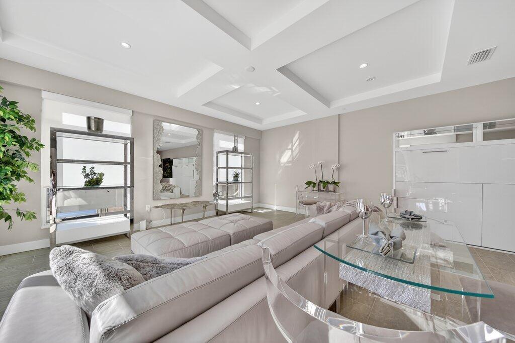 A modern living room features a large gray sectional sofa, glass-topped table, and mirrored accents — 41 SW Seminole Street # 209, Stuart FL 34994, STUART, FL