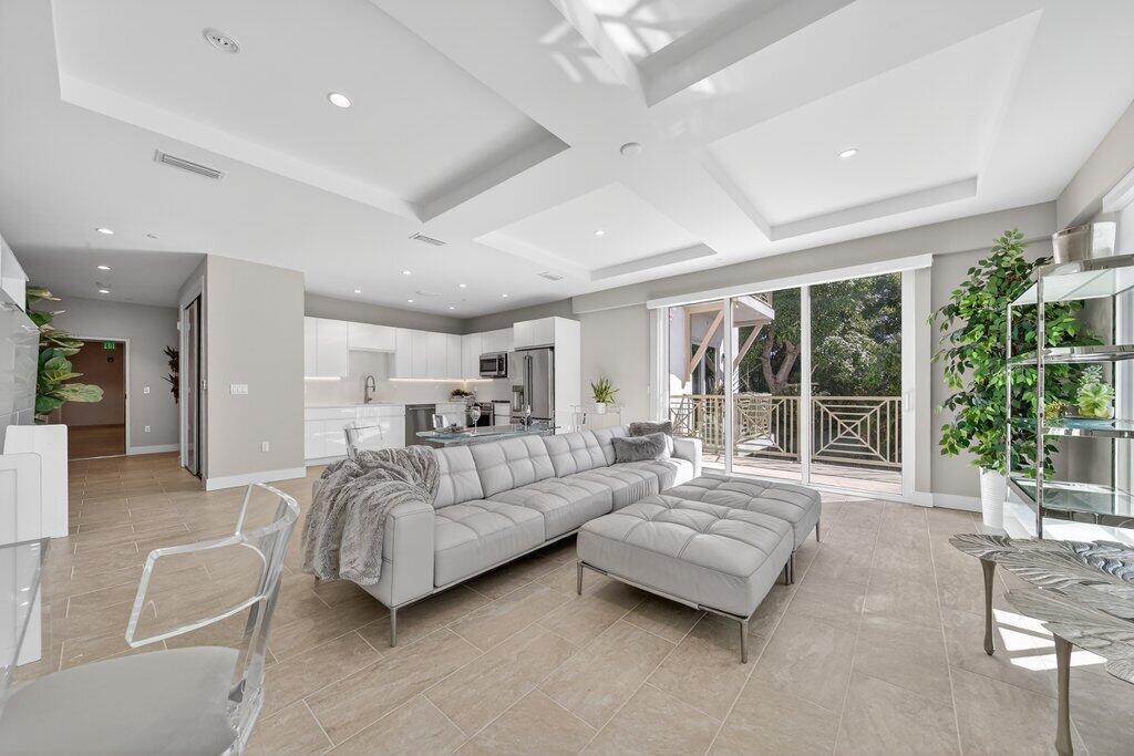A modern open-concept living room and kitchen featuring light tile floors and a gray sofa — 41 SW Seminole Street # 209, Stuart FL 34994, STUART, FL