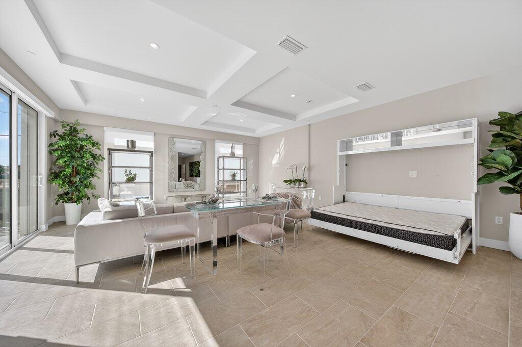 A modern living room features a white Murphy bed, a glass dining table, and tile flooring — 41 SW Seminole Street # 209, Stuart FL 34994, STUART, FL