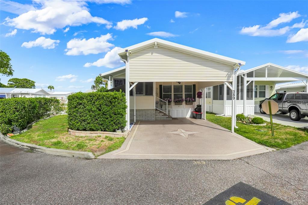 A single-story manufactured home with a carport, concrete driveway, and a manicured hedge — 9000 US HIGHWAY 192 UNIT 389, CLERMONT, FL