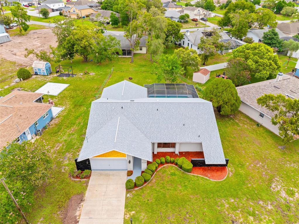 An aerial view shows a single-story house with a gray roof and a screened pool — 13445 BANNER ROAD, SPRING HILL, FL