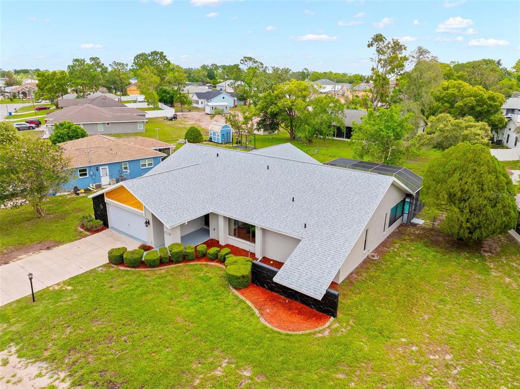 An aerial view of a single-story house with a gray roof and a screened pool — 13445 BANNER ROAD, SPRING HILL, FL
