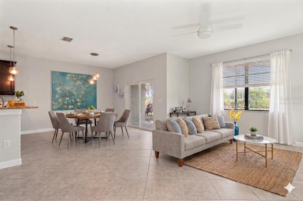 An open-concept living and dining area with tile floors, a sofa, and a round table — 3281 GENTLE DELL, WESLEY CHAPEL, FL