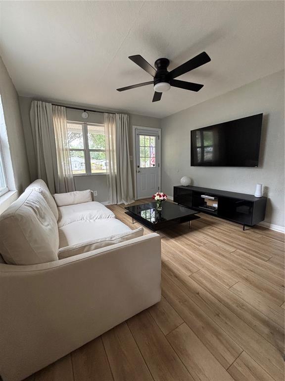 A living room features light wood-look flooring, a white sofa, and a black media console — 4420 DR MARTIN LUTHER KING JR STREET N, ST PETERSBURG, FL