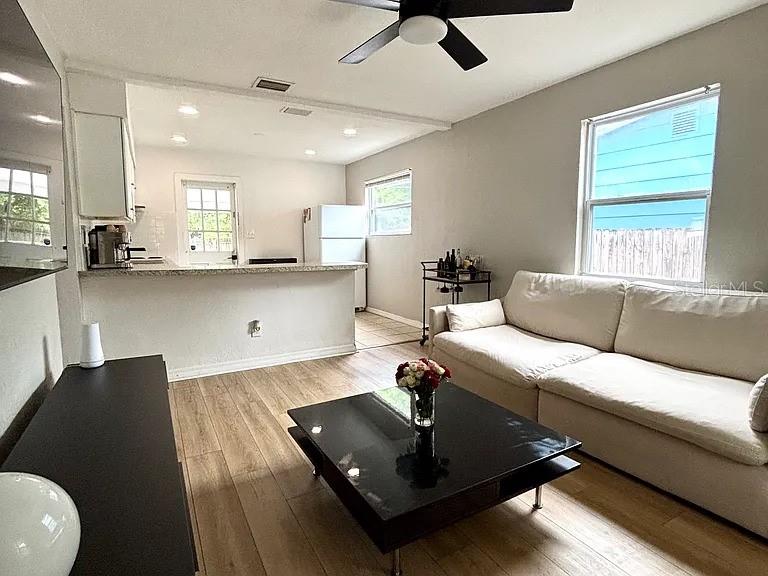 A living room with light wood floors, a white sofa, and an open kitchen area — 4420 DR MARTIN LUTHER KING JR STREET N, ST PETERSBURG, FL