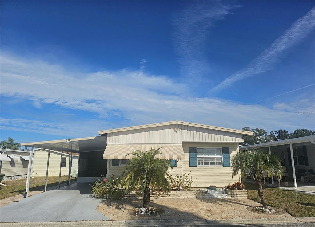 A single-story manufactured home with a carport, light siding, and a small front patio — 3317 OVERCUP OAK TERRACE, SARASOTA, FL
