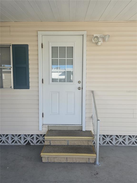 A white exterior door with a window sits above two concrete steps with railings — 3317 OVERCUP OAK TERRACE, SARASOTA, FL