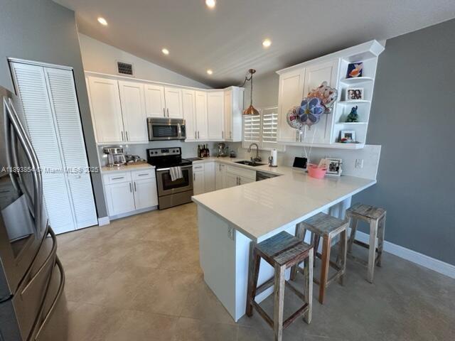 A kitchen features white cabinets, stainless steel appliances, a breakfast bar, and tile flooring — 62 Waterways Dr, Key Largo FL 33037, KEY LARGO, FL