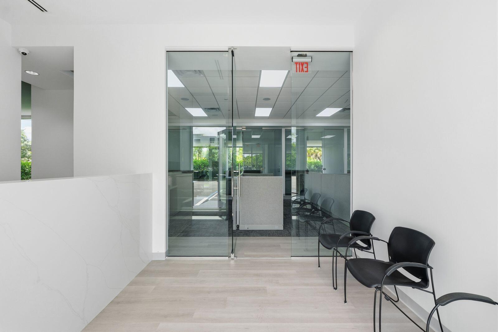 A waiting area features light wood flooring, two black chairs, and glass double doors — 1300 S Dixie Highway # 14, Lantana FL 33462, LANTANA, FL