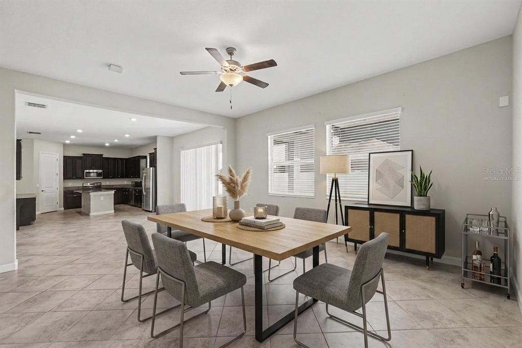 A dining room with a wooden table, gray chairs, and a view into the kitchen — 11701 NAVAJO SANDSTONE STREET, RIVERVIEW, FL
