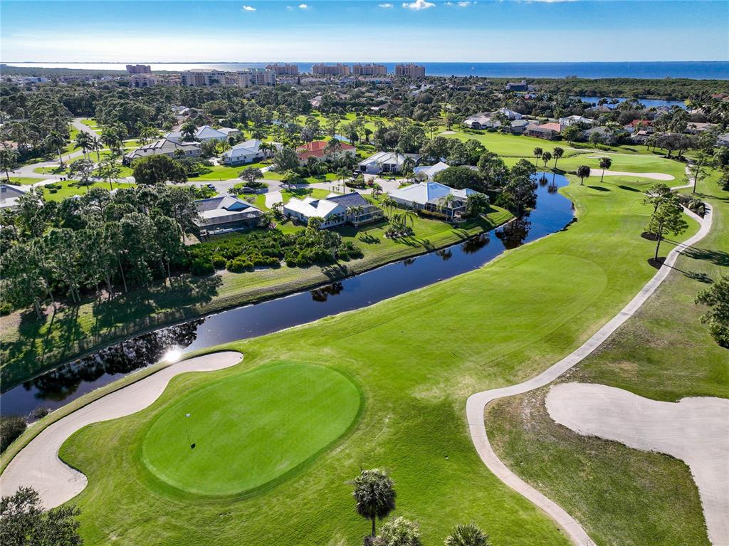 An aerial view of a golf course green, a winding canal, and surrounding residential homes — 3170 MATECUMBE KEY ROAD UNIT 112, PUNTA GORDA, FL