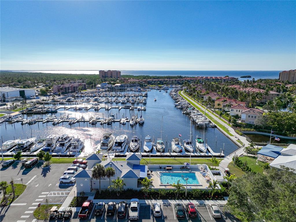 An aerial view shows a marina with numerous docked boats, a swimming pool, and parking — 3170 MATECUMBE KEY ROAD UNIT 112, PUNTA GORDA, FL