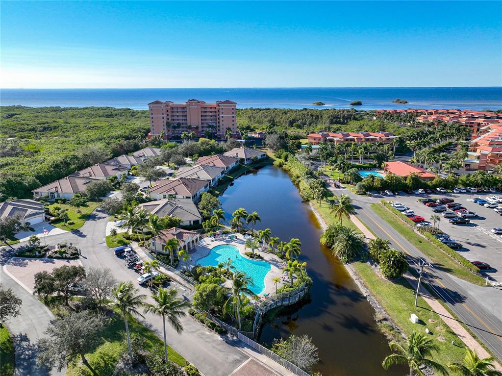 An aerial view shows a resort complex with a swimming pool, pond, and multi-story buildings — 3170 MATECUMBE KEY ROAD UNIT 112, PUNTA GORDA, FL