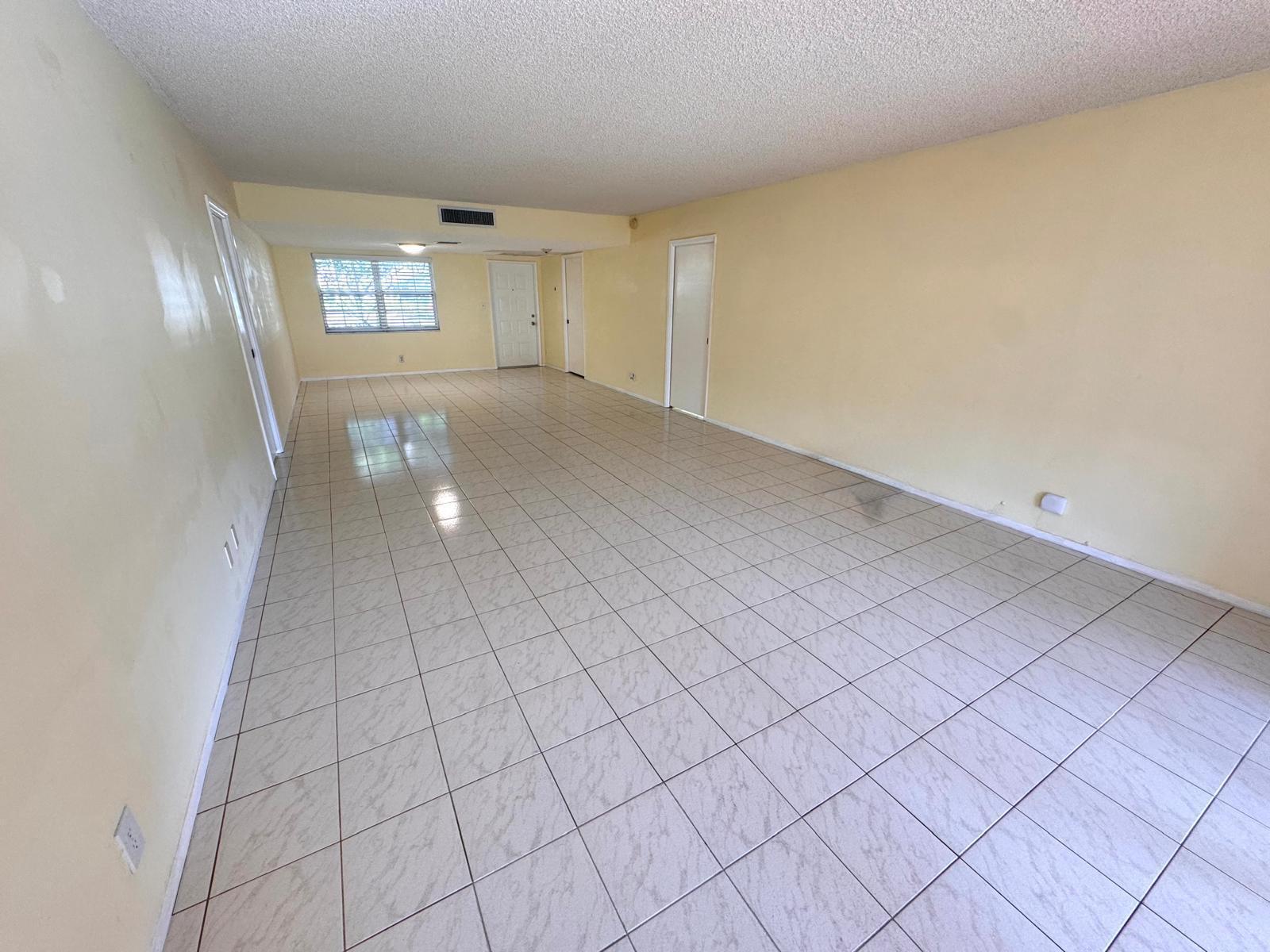 An empty room with light-colored tile flooring, pale yellow walls, and a textured ceiling — 901 Cypress Terrace # 103, Pompano Beach FL 33069, POMPANO BEACH, FL