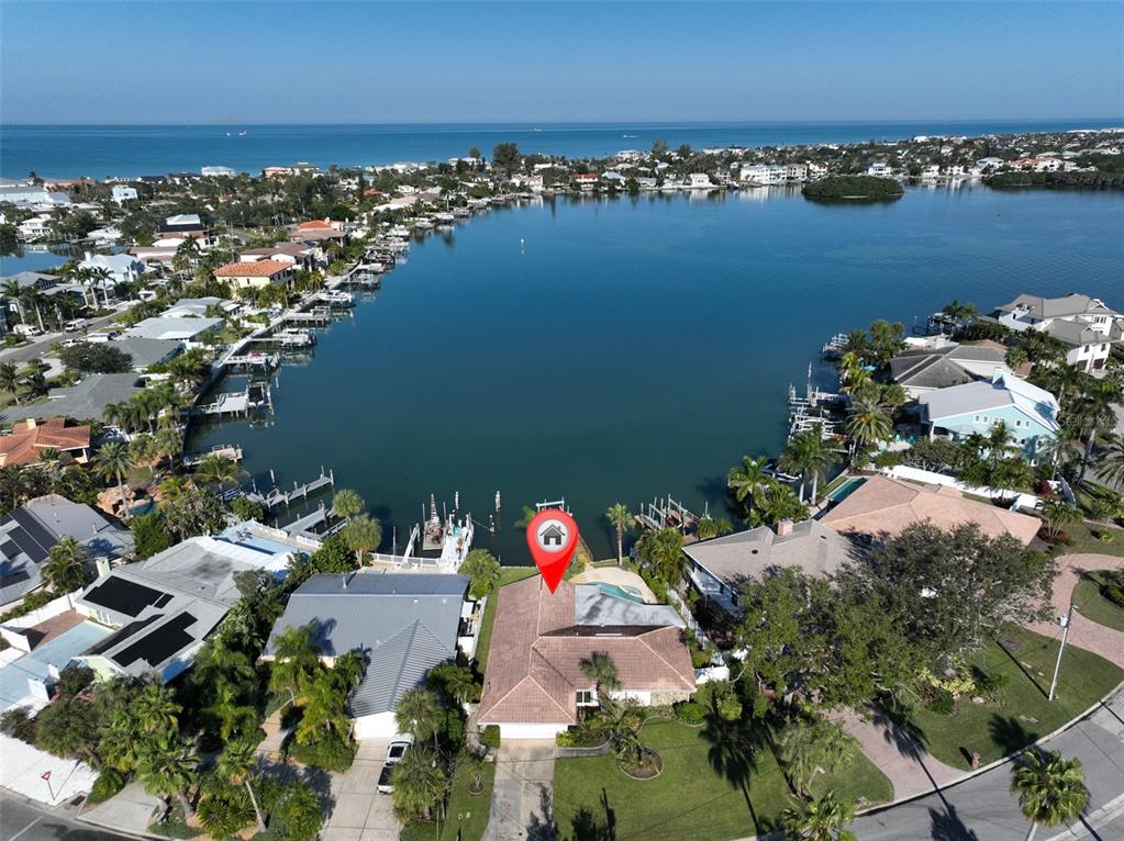 An aerial view shows a waterfront house with a pool and dock on a bay — 410 HARBOR DRIVE N, INDIAN ROCKS BEACH, FL