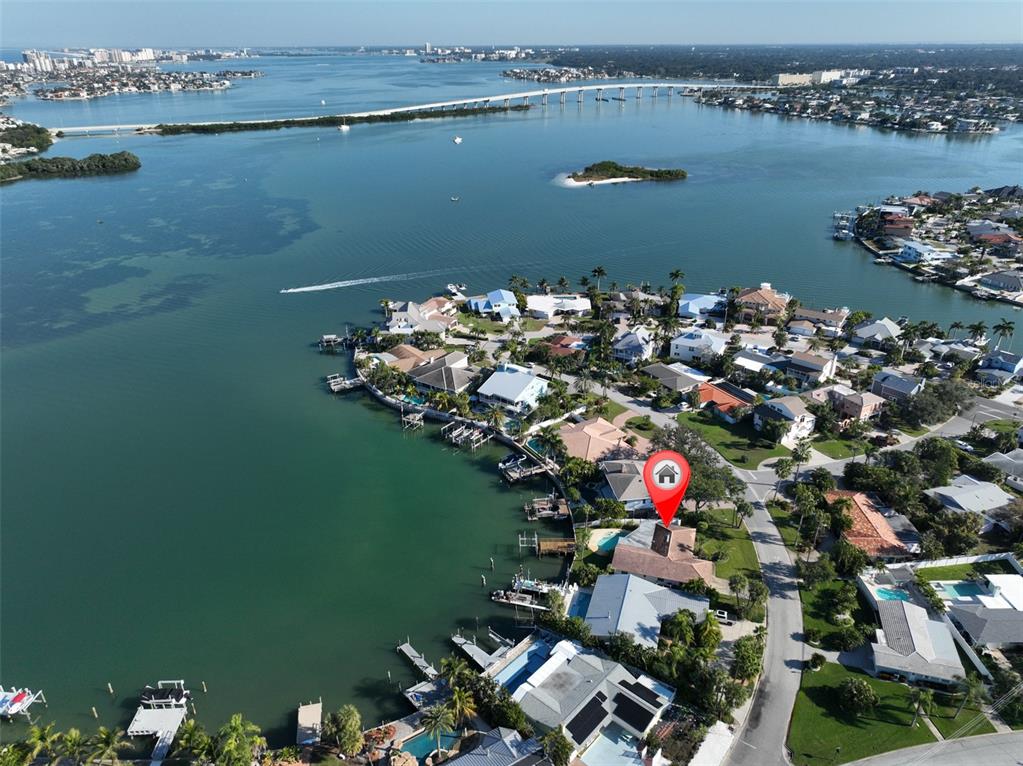 An aerial view shows a waterfront house with a pool and dock on a peninsula — 410 HARBOR DRIVE N, INDIAN ROCKS BEACH, FL