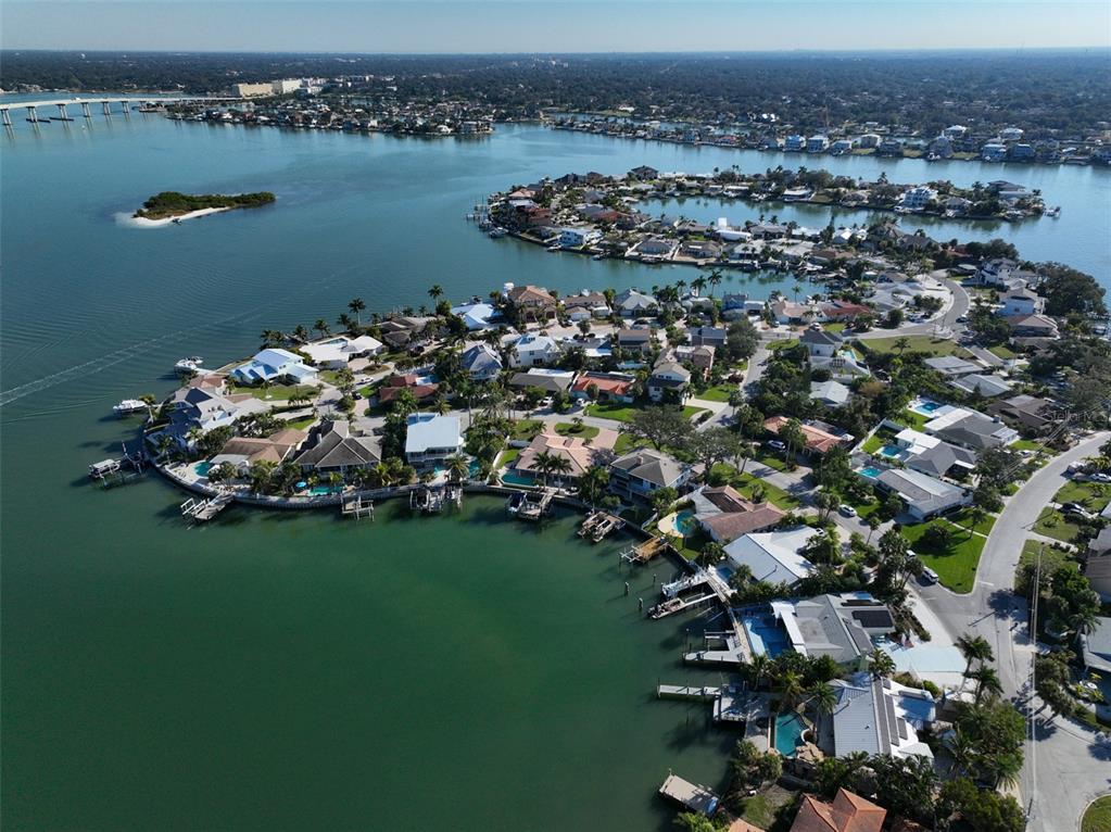 An aerial view shows waterfront homes with private docks along a coastal residential peninsula — 410 HARBOR DRIVE N, INDIAN ROCKS BEACH, FL