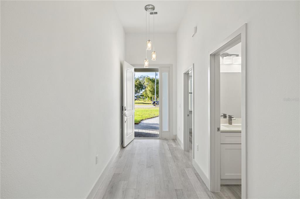 A bright entryway with light wood-look flooring, a pendant light fixture, and an open door — 21021 PEACHLAND BOULEVARD, PORT CHARLOTTE, FL