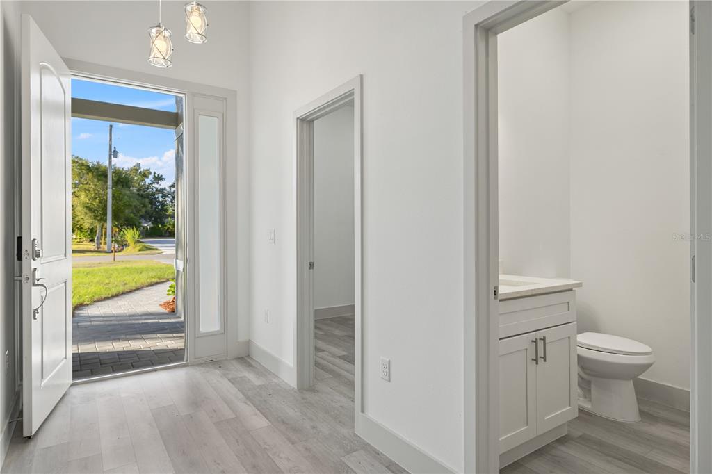 An entryway with light wood-look flooring leads to a small bathroom and an interior room — 21021 PEACHLAND BOULEVARD, PORT CHARLOTTE, FL