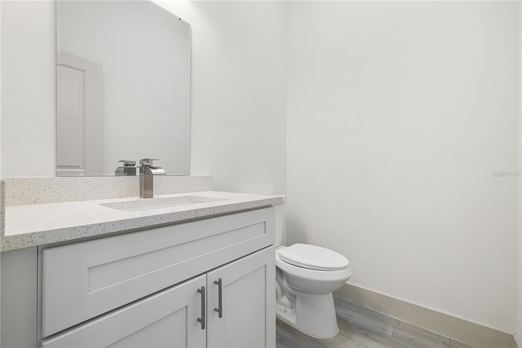 A modern bathroom features a white vanity with a quartz countertop, mirror, and toilet — 21021 PEACHLAND BOULEVARD, PORT CHARLOTTE, FL