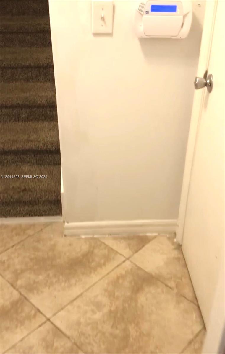 A tiled entryway features a carpeted staircase and a wall-mounted security system panel — 2490 Centergate Dr # 207, Miramar FL 33025, MIRAMAR, FL