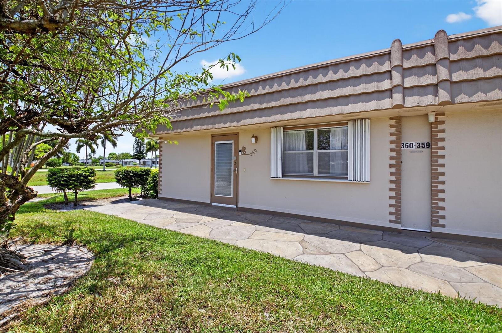 A single-story building exterior features a stone walkway, a front door, and a window — 360 Seville # O, Delray Beach FL 33446, DELRAY BEACH, FL