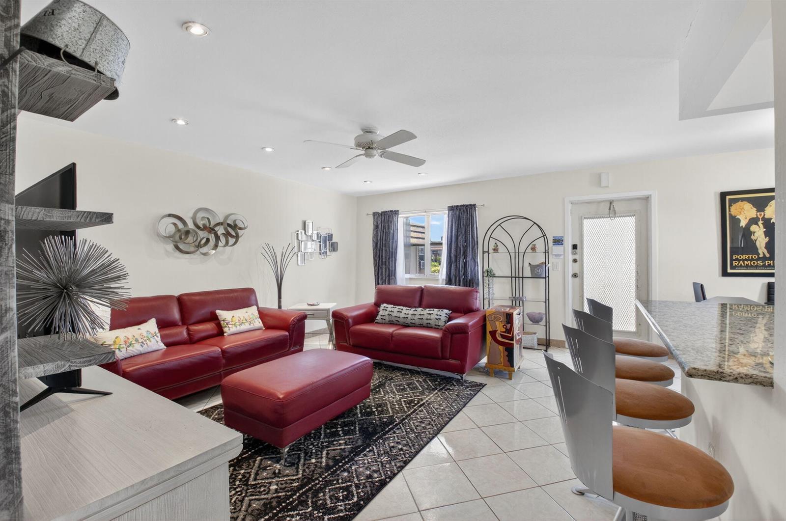 A living room features red leather sofas, a matching ottoman, and a breakfast bar area — 360 Seville # O, Delray Beach FL 33446, DELRAY BEACH, FL