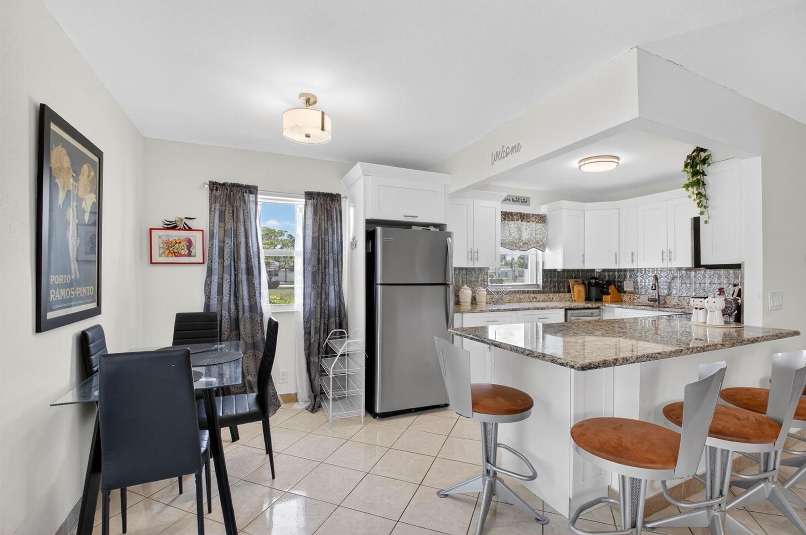 A kitchen and dining area with white cabinets, granite countertops, and a glass dining table — 360 Seville # O, Delray Beach FL 33446, DELRAY BEACH, FL