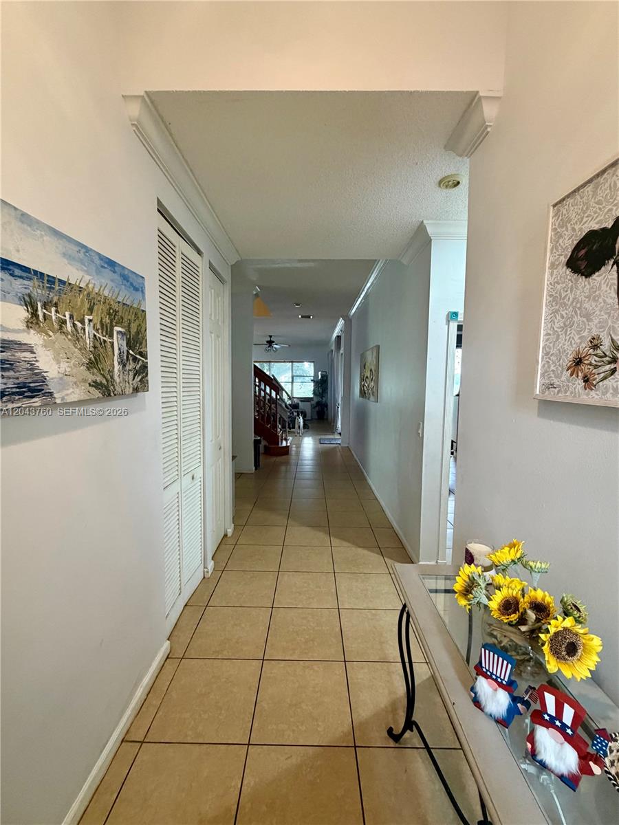 A tiled hallway leads past a closet and wall art toward a staircase — 13193 SW 30th St, Miramar FL 33027, MIRAMAR, FL