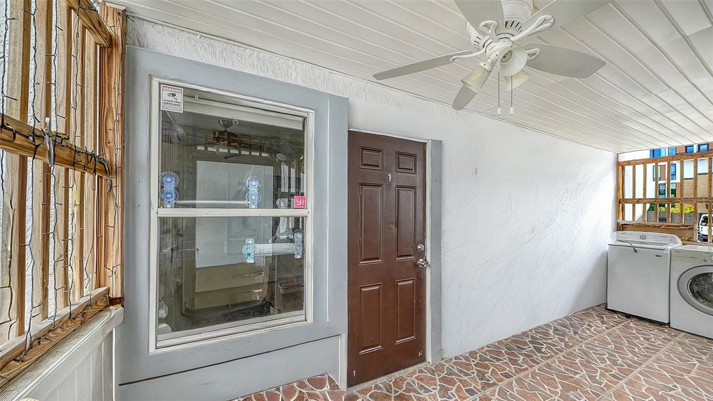 A covered patio features a brown door, a window, a ceiling fan, and laundry appliances — 420 KUMQUAT COURT, SARASOTA, FL