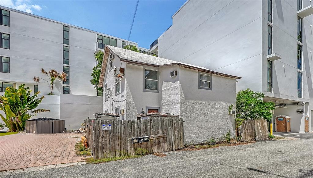 A small, two-story white house sits between two large modern apartment buildings — 420 KUMQUAT COURT, SARASOTA, FL