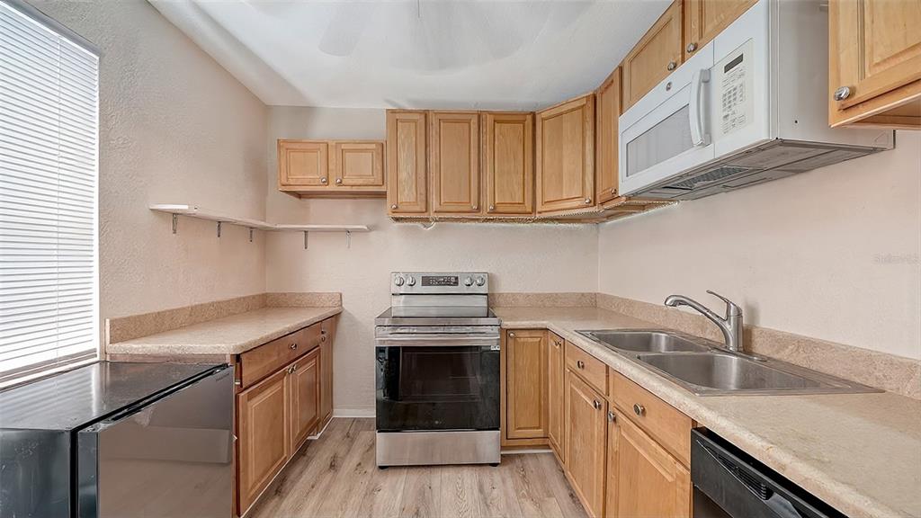 A kitchen with light wood cabinets, stainless steel appliances, and laminate countertops — 420 KUMQUAT COURT, SARASOTA, FL