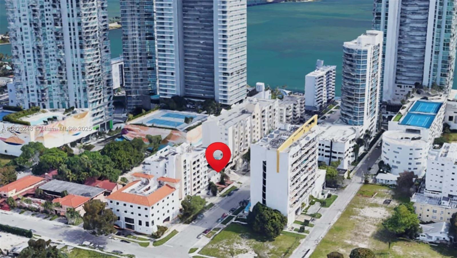This aerial view shows a residential neighborhood with apartment buildings and tennis courts near water — 437 NE 30th St, Miami FL 33137, MIAMI, FL