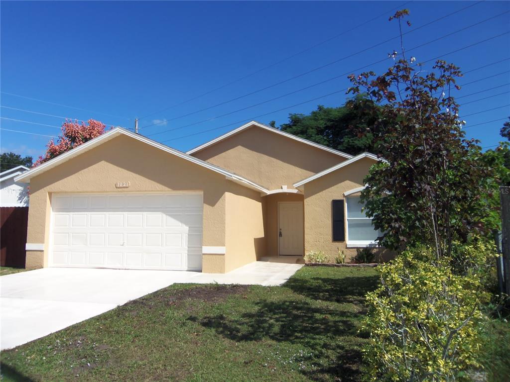 A tan single-story house with a two-car garage and a front entrance under a portico — 1021 GOLFSIDE COURT, KISSIMMEE, FL