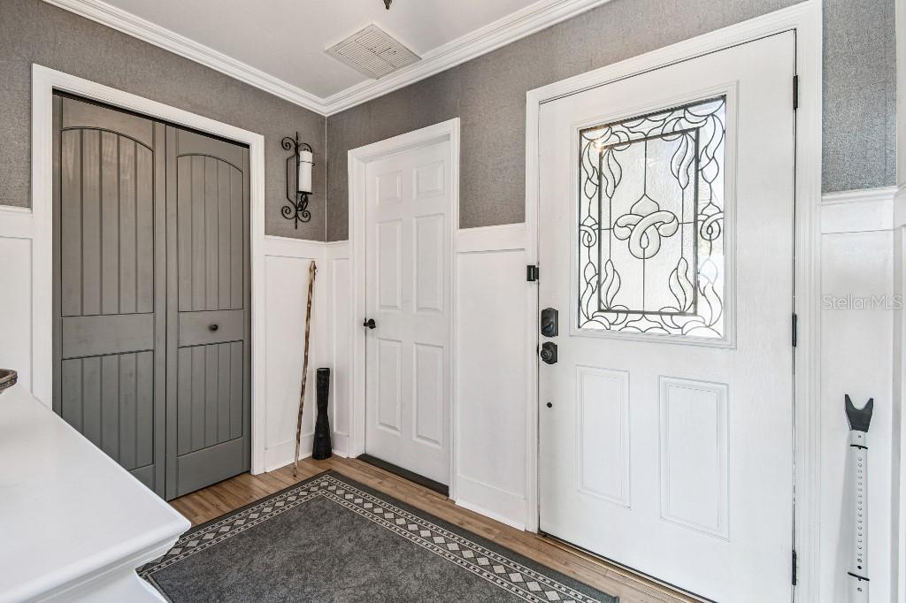An entryway features a white front door, a gray closet, and white wainscoting on gray walls — 6408 RUNNING BEAR DRIVE, LAKELAND, FL