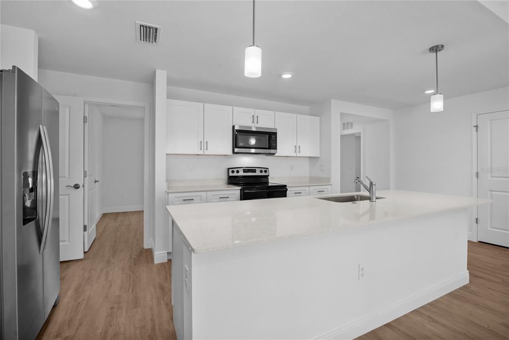 A modern kitchen features white cabinetry, a large quartz island, and stainless steel appliances — 23377 AVACADO AVENUE, PORT CHARLOTTE, FL