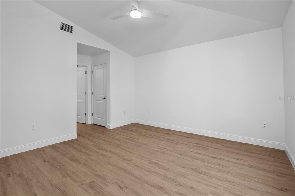 An empty bedroom features white walls, light wood-look flooring, and a ceiling fan — 23377 AVACADO AVENUE, PORT CHARLOTTE, FL
