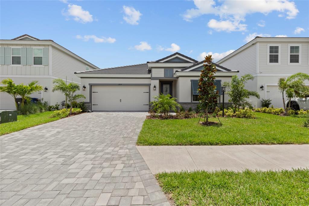 A single-story house with a paved driveway, a two-car garage, and landscaped front yard — 17814 CROPSIDE TRAIL, BRADENTON, FL