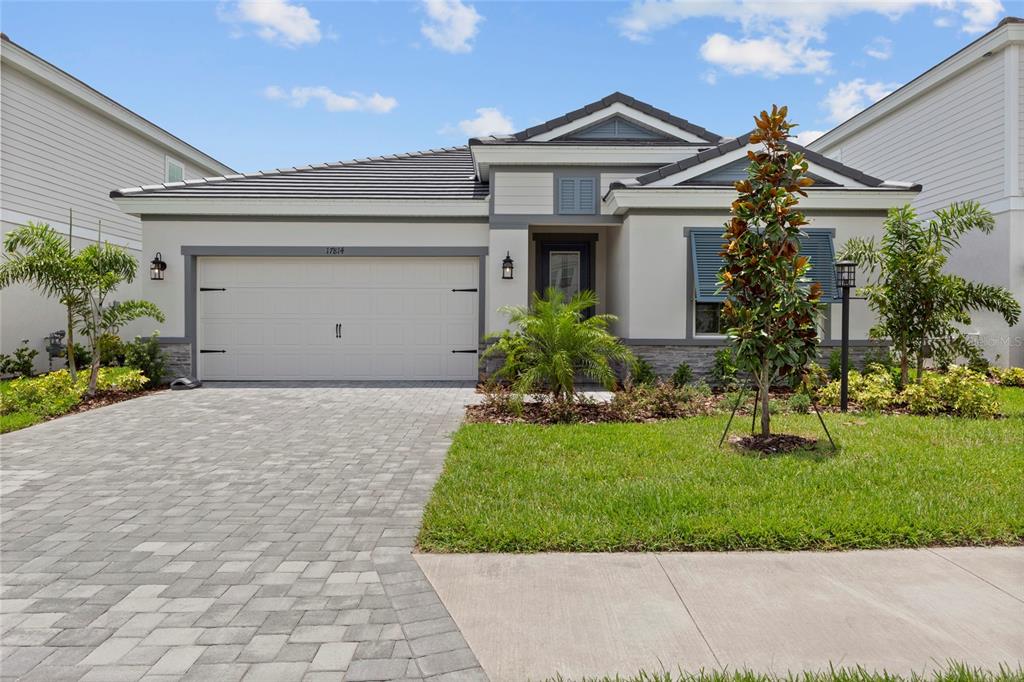 A single-story house with a paved driveway, a two-car garage, and a landscaped front yard — 17814 CROPSIDE TRAIL, BRADENTON, FL