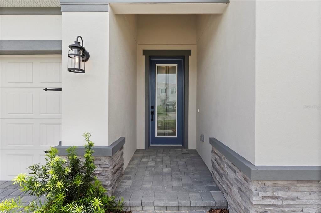 A front entryway features a blue door, stone veneer accents, and a paved walkway — 17814 CROPSIDE TRAIL, BRADENTON, FL