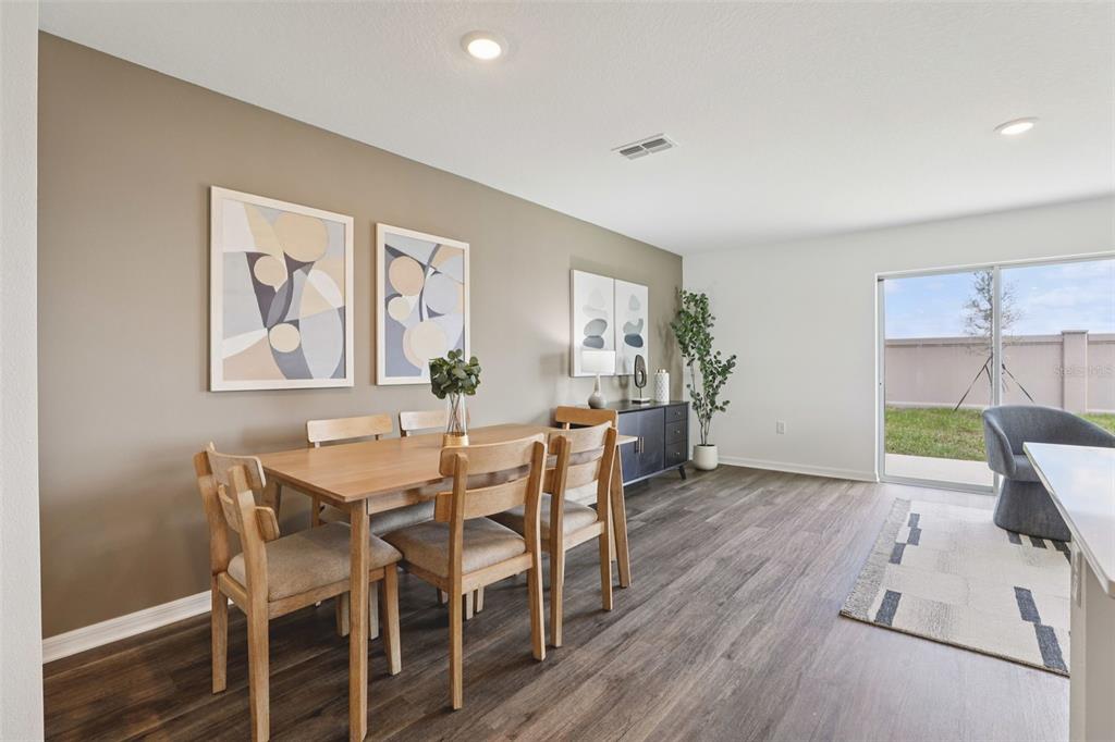 A dining area features a wooden table, chairs, wall art, and sliding glass doors — 2350 AVEENO AVENUE, HAINES CITY, FL