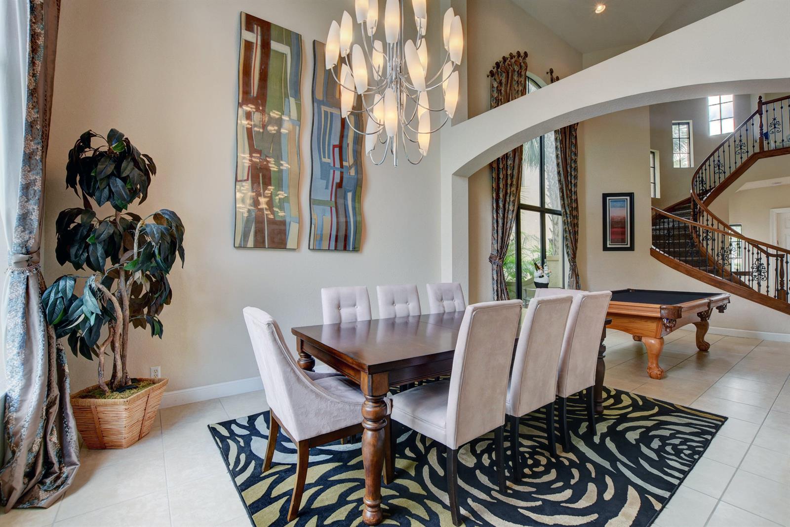 A dining room features a wooden table, upholstered chairs, a chandelier, and a pool table — 3424 Collonade Drive, Wellington FL 33449, WELLINGTON, FL