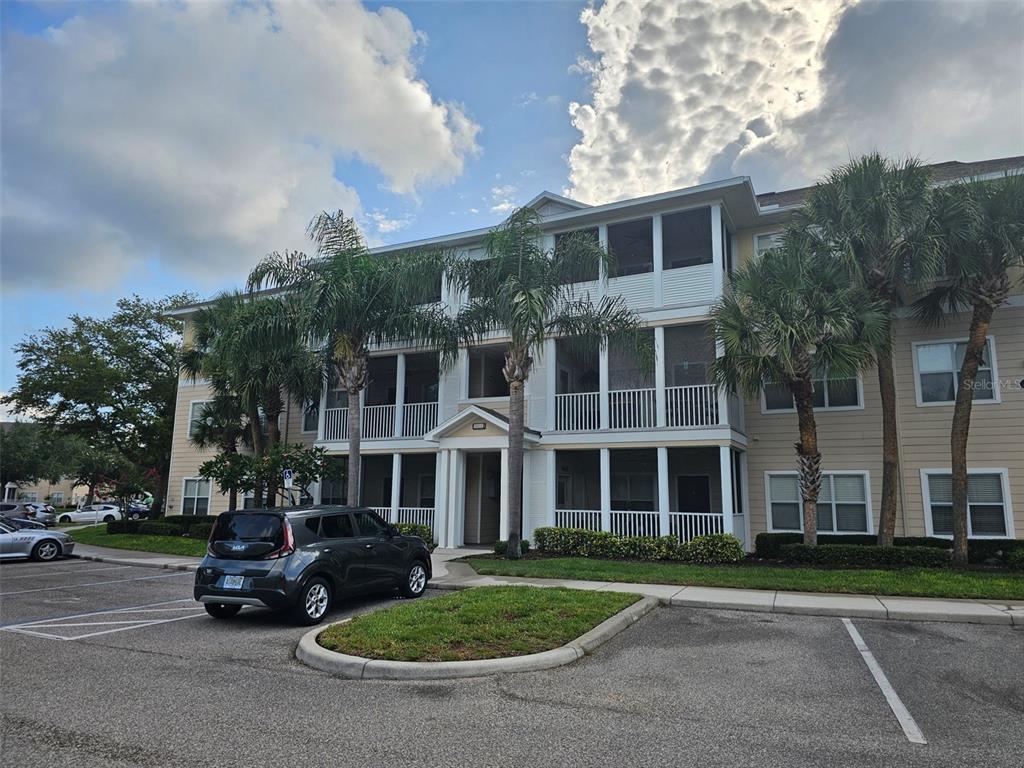 A three-story apartment building with screened balconies and palm trees in a parking lot — 4802 51ST STREET W UNIT 1610, BRADENTON, FL
