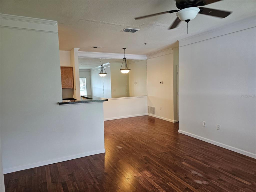 An open-concept living and dining area features hardwood floors, a ceiling fan, and mirrored walls — 4802 51ST STREET W UNIT 1610, BRADENTON, FL