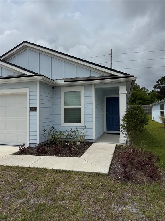 A light blue single-story house features a white garage door and a dark blue front door — 203 CHESTERWOOD ROAD, ST AUGUSTINE, FL