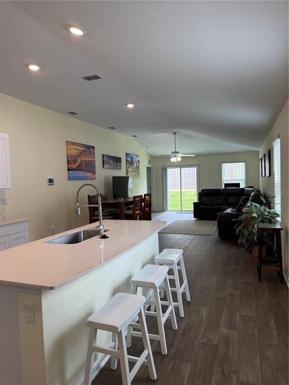 An open-concept kitchen with a white island and stools overlooks a living area — 203 CHESTERWOOD ROAD, ST AUGUSTINE, FL