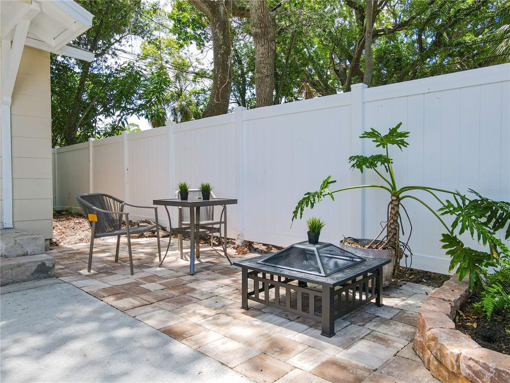 A patio with a fire pit, a small table, two chairs, and a white privacy fence — 609 N OSCEOLA AVENUE UNIT A & B, CLEARWATER, FL