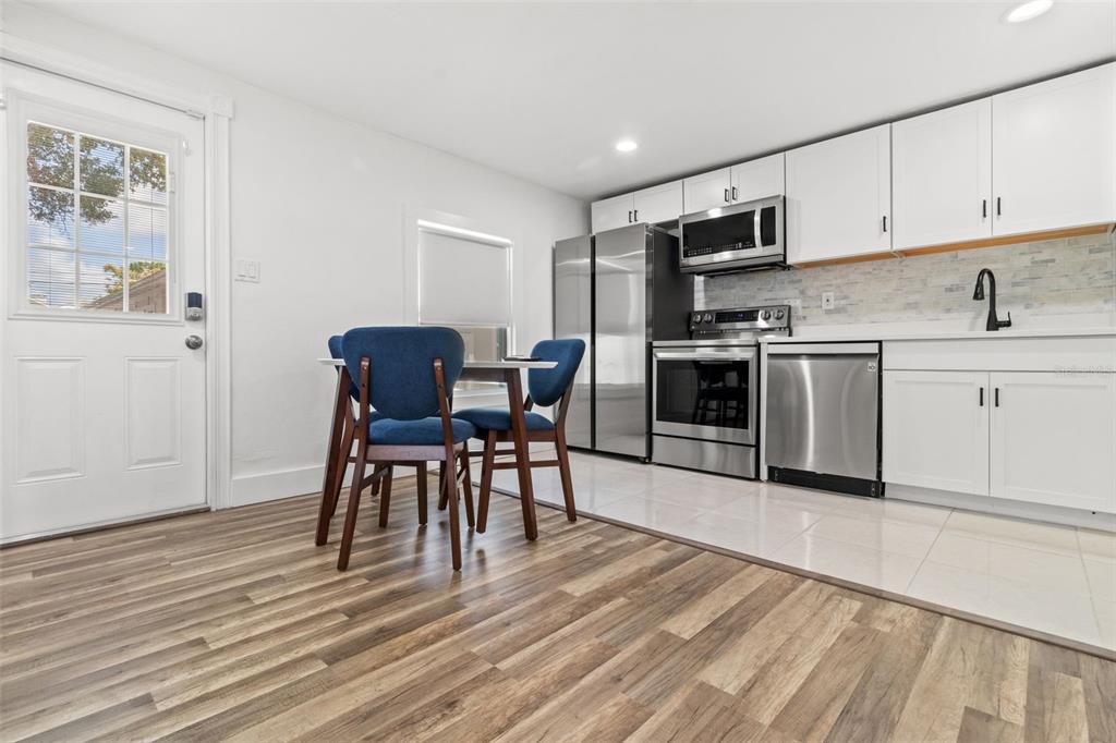 A kitchen with white cabinets, stainless steel appliances, and a small dining table with chairs — 609 N OSCEOLA AVENUE UNIT A & B, CLEARWATER, FL
