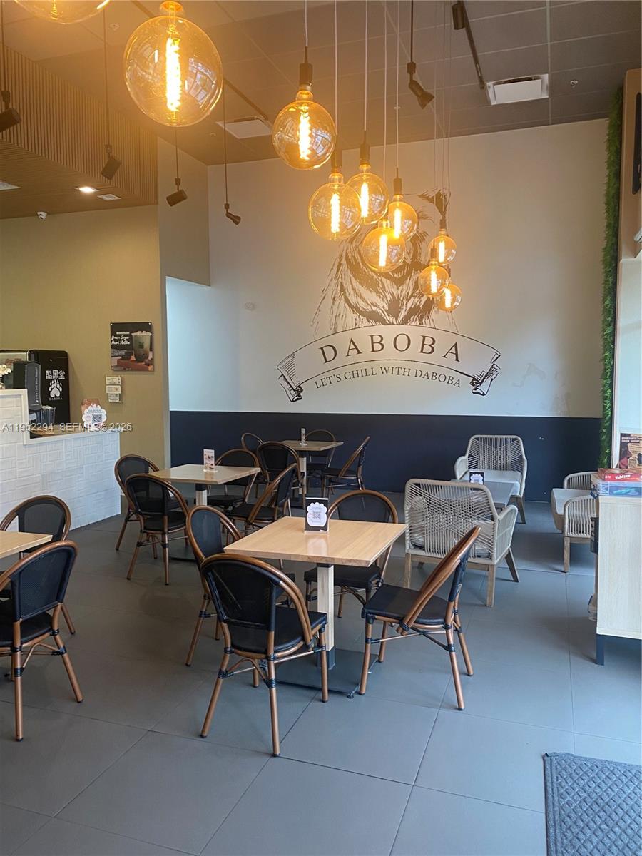 A brightly lit bubble tea shop features wooden tables, black chairs, and a bear-themed wall mural — 8711 SW 124th Ave, Miami FL 33183, MIAMI, FL