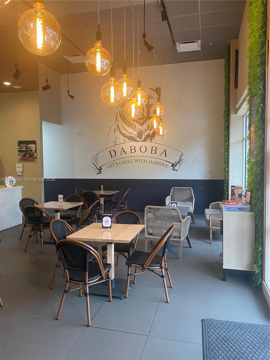 A cafe interior features wooden tables, black chairs, pendant lighting, and a bear wall mural — 8711 SW 124th Ave, Miami FL 33183, MIAMI, FL